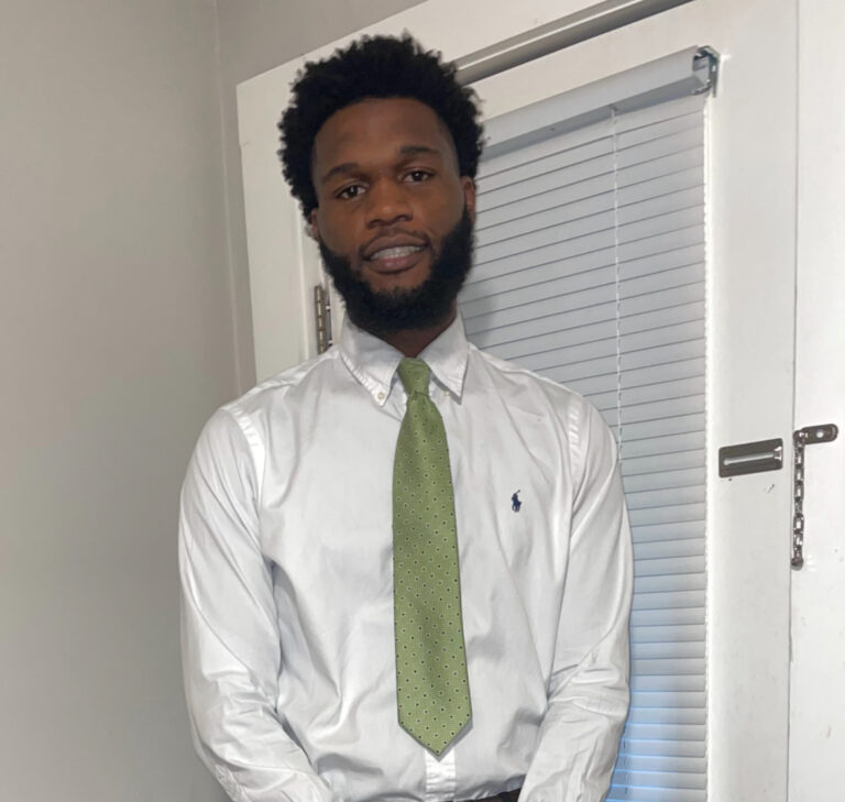 Umar Muhammad smiling in an indoor setting.