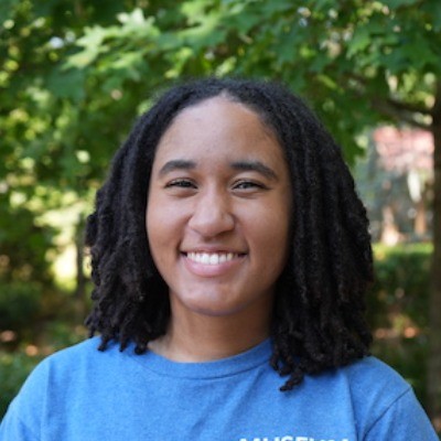 Amaya Horner smiling in an outdoor space in front of a tree.