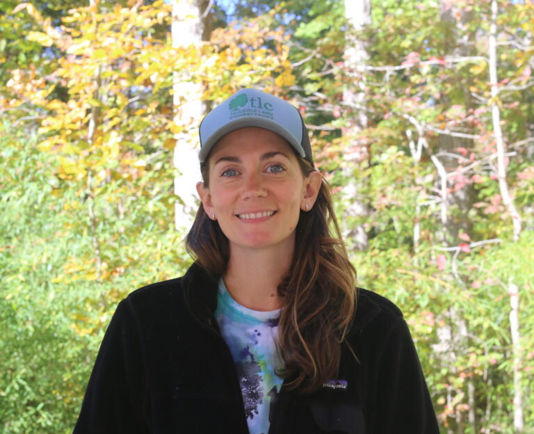 Hannah Royal smiling in front of a dense forest background.